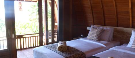 Una habitación de madera con dos camas, cada una con ropa blanca y almohadas estampadas.