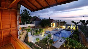 Vista de varanda com piscina, uma casa pequena e uma praia.