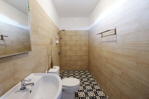 A bathroom with a white sink, toilet, and shower. The floor has a black and white patterned tile design.