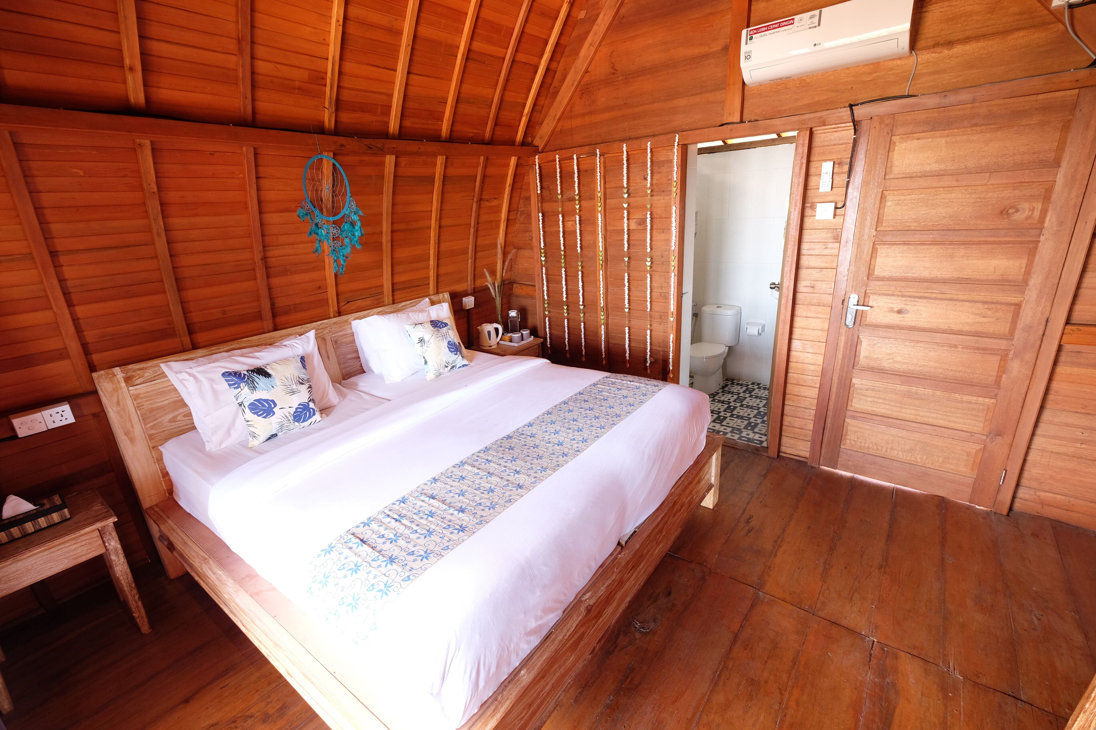 A wooden room with a bed, bedside table, and a wardrobe.