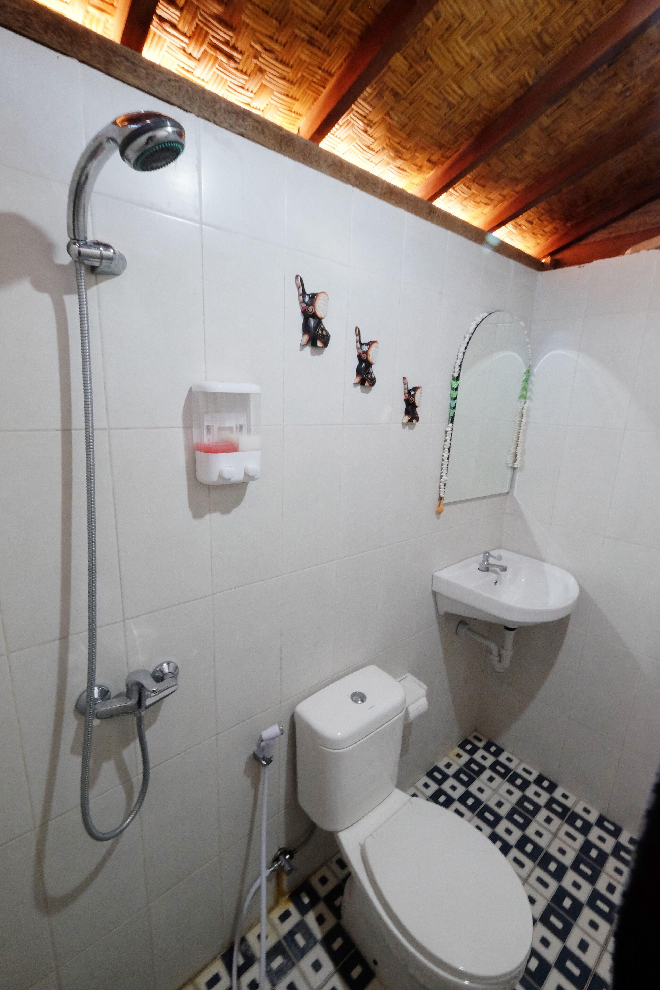 Un baño con ducha, inodoro, lavamanos y elementos decorativos en la pared.