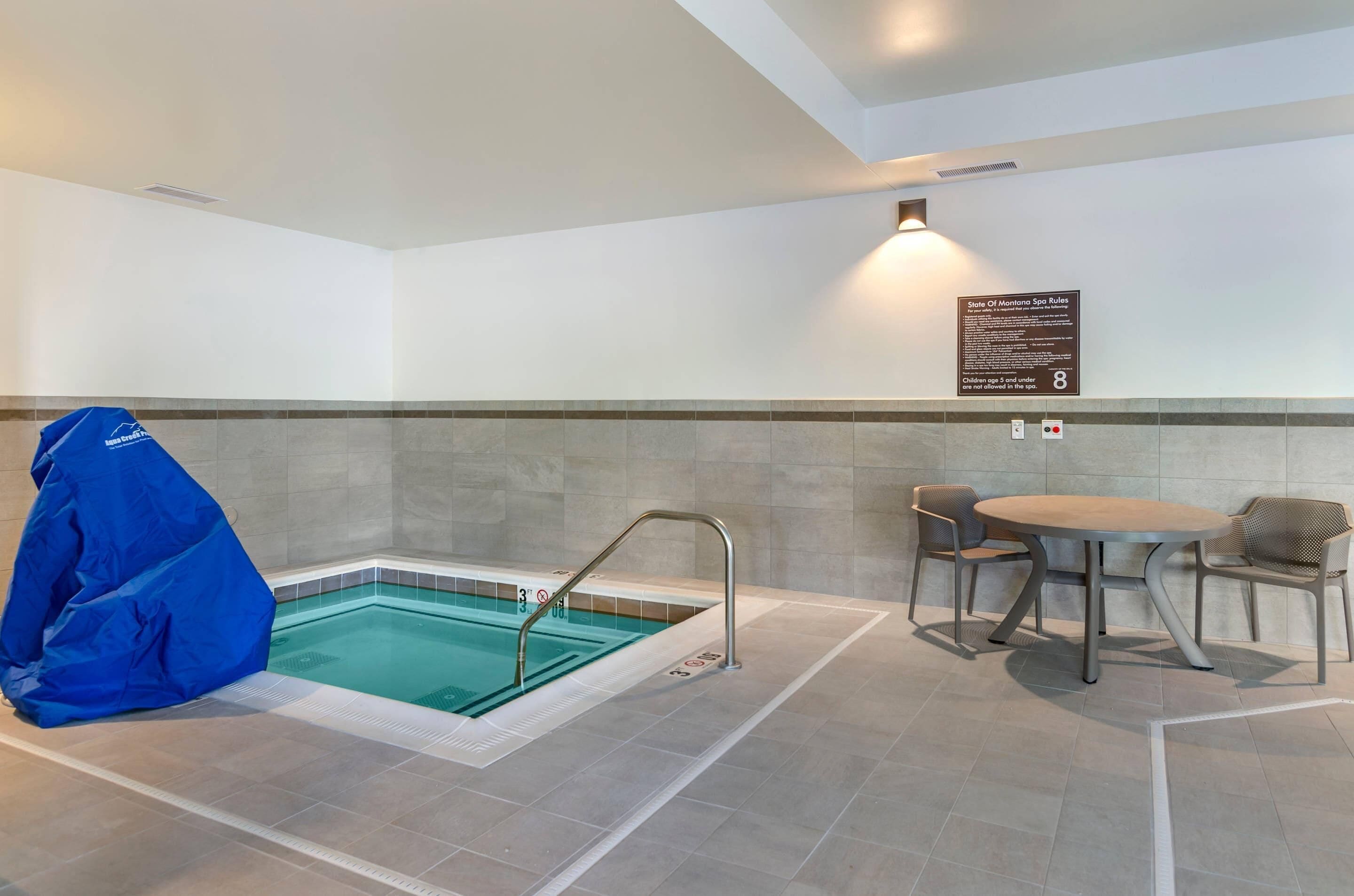 Un área de piscina con una zona de estar techada y un cartel que detalla las normas del spa.