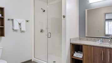 A modern bathroom with a glass-enclosed shower, a wooden vanity with a granite countertop, and a large mirror above the sink.