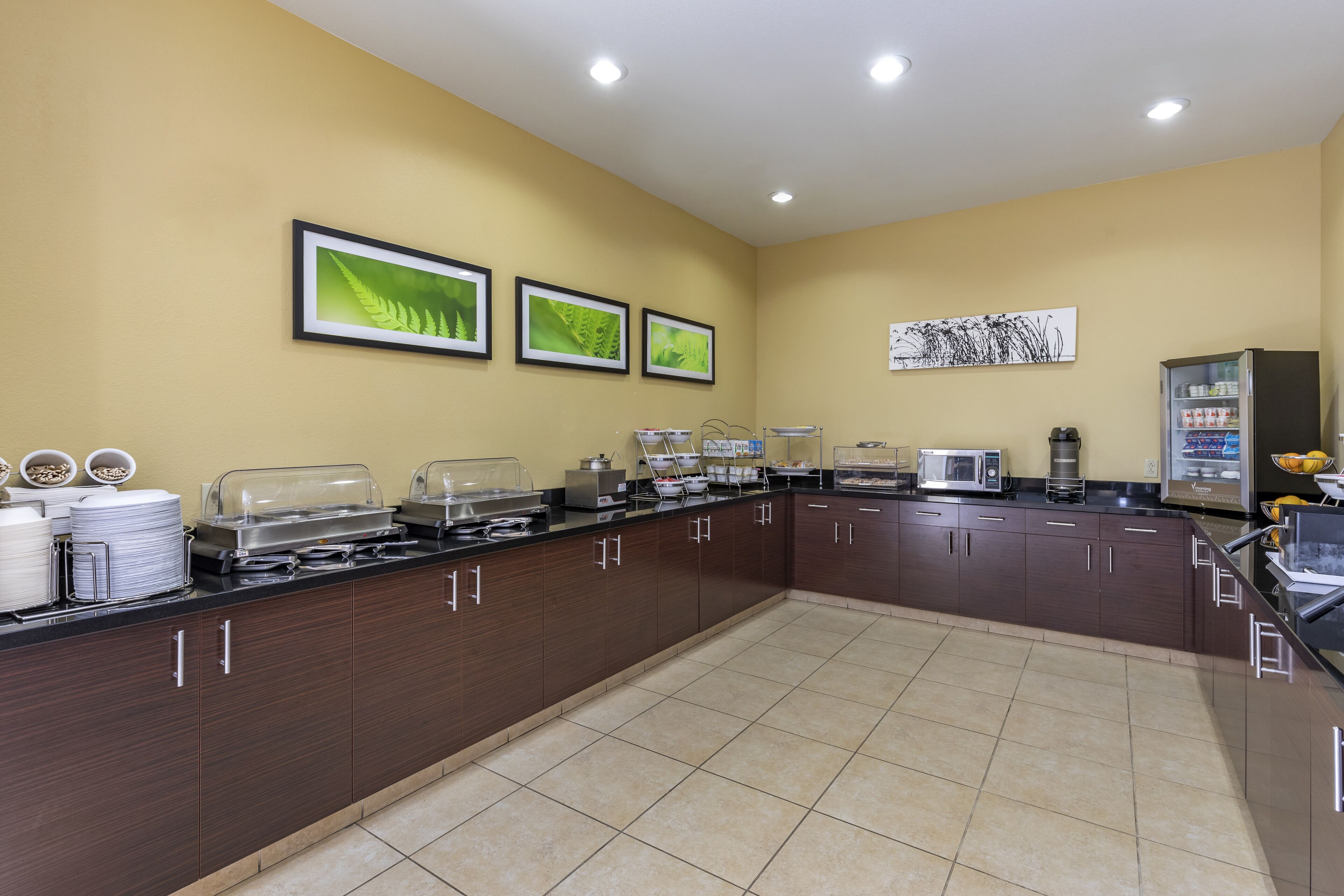 Una cocina moderna con una encimera larga, equipada con diferentes electrodomésticos y dispensadores de alimentos.