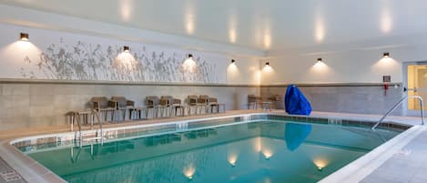 Ein überdachter Swimmingpool mit klarem Wasser, umgeben von Liegestühlen und einer Wand mit einer Pflanzenwand.