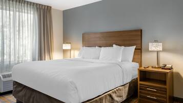 A hotel room with a large bed, bedside lamps, a nightstand, and a window with curtains.