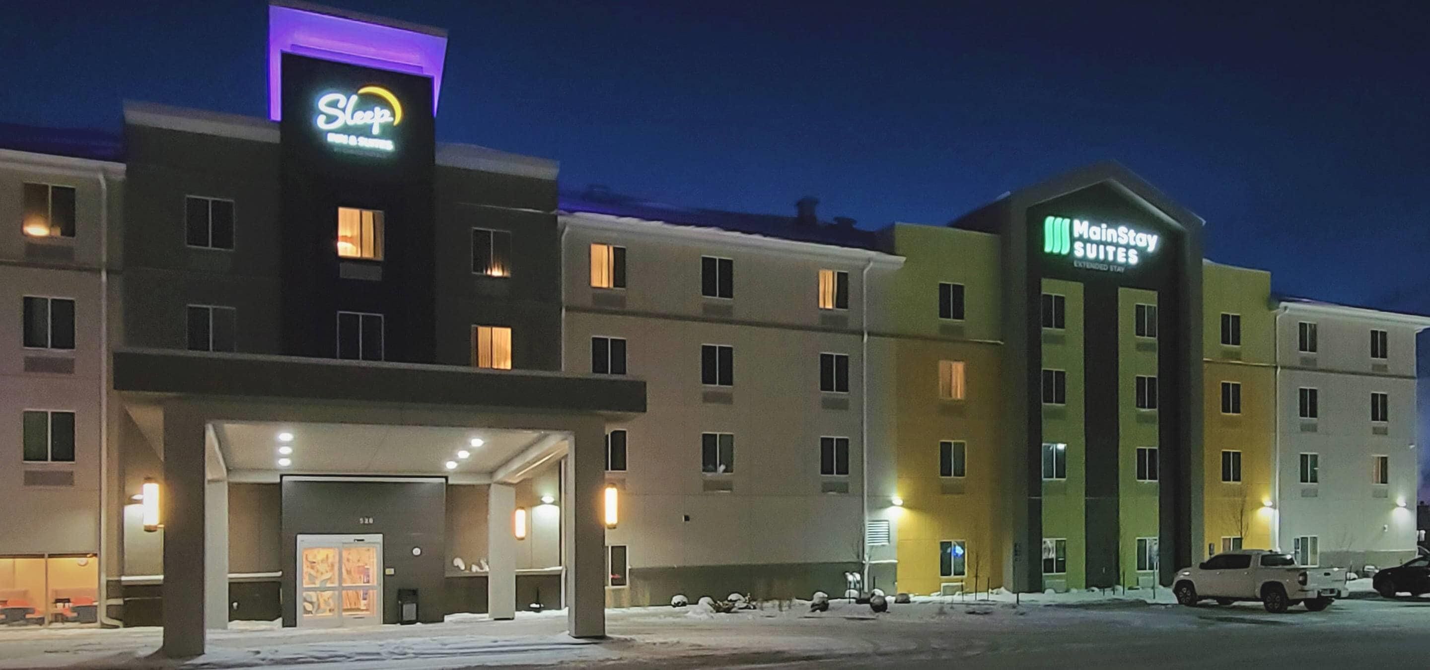 Un hotel con ingresso principale, un cartello con la scritta 'MainStay Suites' e un'insegna con la parola 'Sleep' sopra l'ingresso.