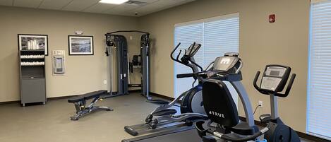 A fitness room with a treadmill, elliptical, and weight machine.