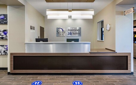 A hotel reception desk with signs for Sleep Inn and MainStay Suites.