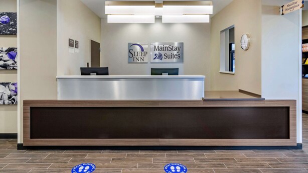 A hotel reception desk with signs for Sleep Inn and MainStay Suites. - Sleep Inn Great Falls Airport (Great Falls)