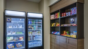 Two refrigerated display cases with snacks and drinks, and a wooden cabinet with various food items. - Sleep Inn Great Falls Airport (Great Falls)