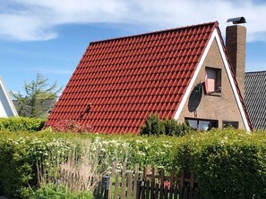 A house with a steep red-tiled roof, a brick chimney, and a small window.