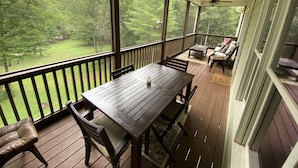 A covered porch with a table and chairs, a ceiling fan, and a view of a green landscape. - Explore, Relax: Mountain House, Yahoola Creek, Cherokee Forest (Dahlonega)