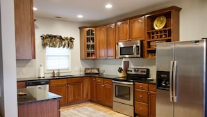 A kitchen with wooden cabinets, stainless steel appliances, and a built-in microwave. - Explore, Relax: Mountain House, Yahoola Creek, Cherokee Forest (Dahlonega)