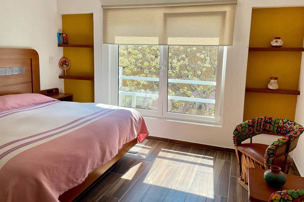 Un dormitorio con una cama, una ventana, una silla y estanterías.