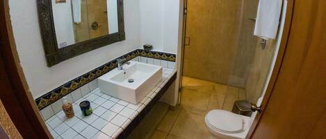 Un baño con lavamanos blanco, espejo y retrete.