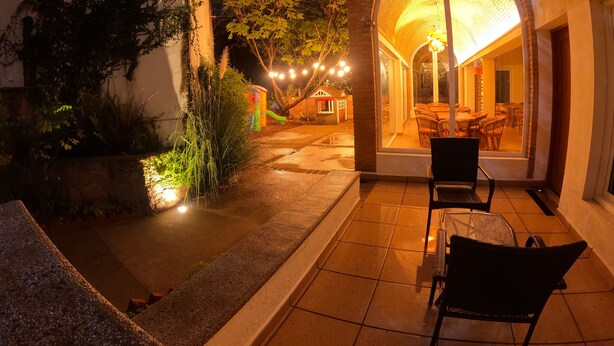 Un patio con mesa y sillas, un pequeño espacio de juegos y un edificio con entrada curva.