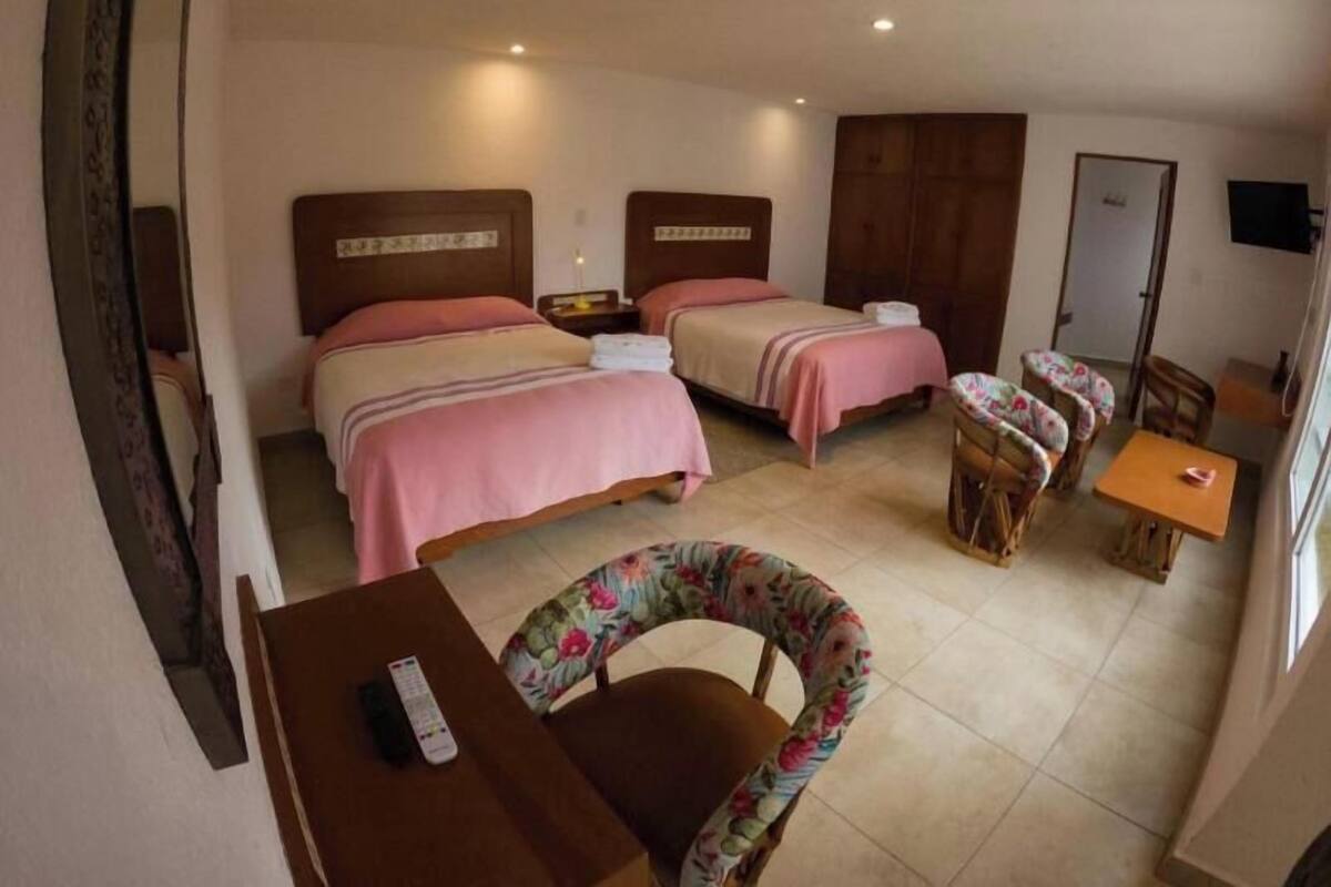 Una habitación de hotel con dos camas, un escritorio, una silla y un televisor.