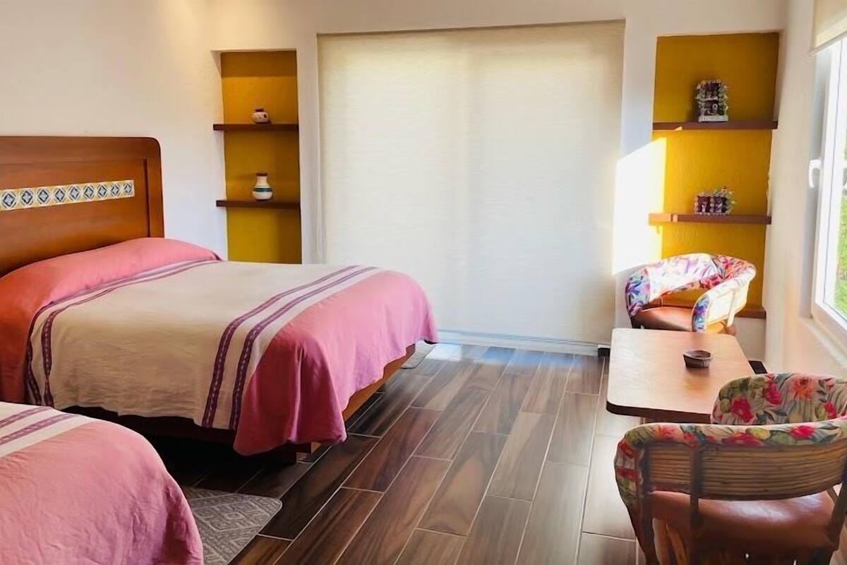 Habitación de hotel con dos camas, una mesita, una silla y ventana con vistas.