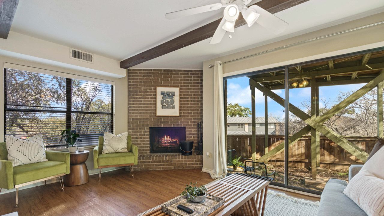 A spacious living room with a fireplace, large windows, and a view of the outdoors.
