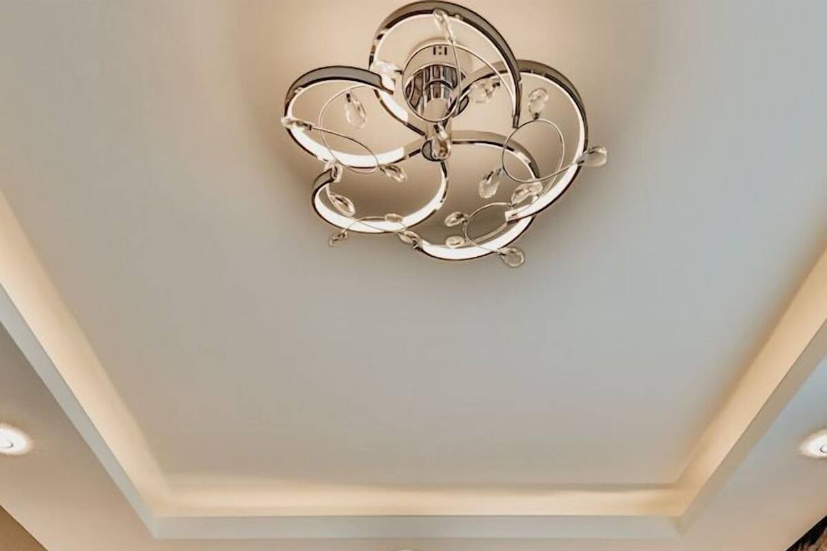 A modern bedroom with a large bed, a decorative ceiling light, and two wall-mounted lamps.