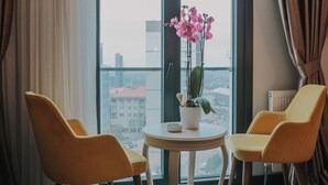 A room with two yellow chairs, a small round table, and a potted orchid plant. - Grand Lark Otel (Istanbul)