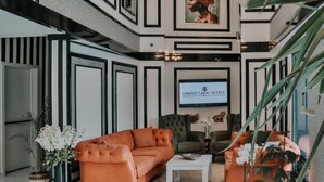 A spacious lobby with a large chandelier, a sectional sofa, and a flat-screen TV displaying the hotel name. - Grand Lark Otel (Istanbul)