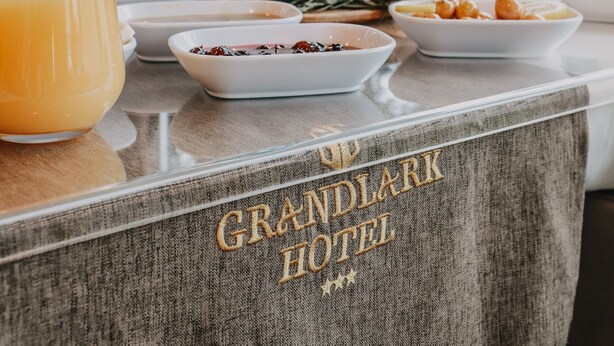 A breakfast table at the Grandlark Hotel with various dishes, a glass of orange juice, and a view of trees outside. - Grand Lark Otel (Istanbul)