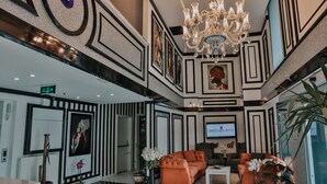 A lobby with a chandelier, sofas, a TV, and framed artwork. - Grand Lark Otel (Istanbul)