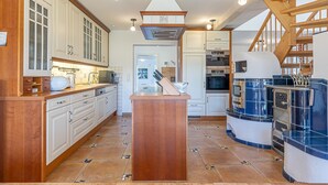 A modern kitchen with wooden cabinetry, a central island, and a built-in oven.
