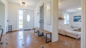 A spacious living area with a white sofa, a wooden bench, and a tiled floor with geometric patterns.