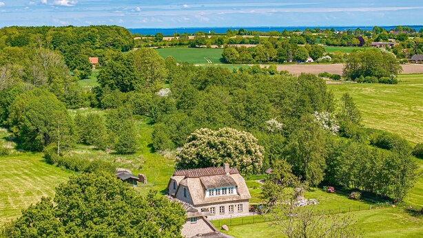 A large estate with a central house surrounded by lush greenery and fields.