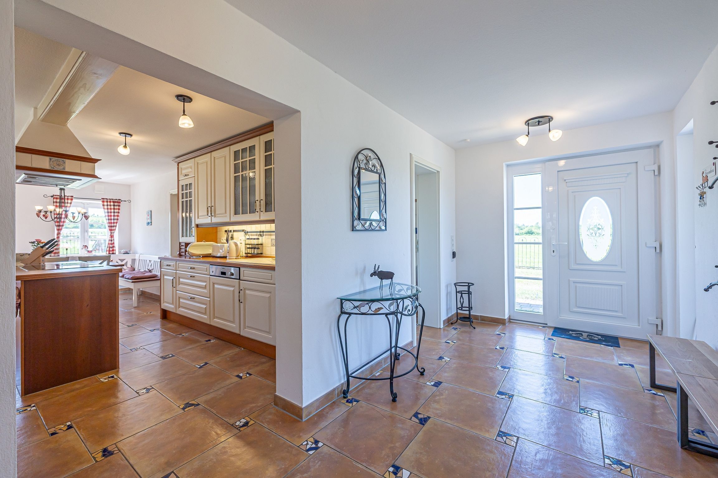 A spacious kitchen with white cabinets, a central island, and a decorative mirror.