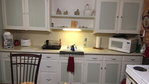 A compact kitchen with white cabinets, a microwave, a coffee maker, and a sink. - Rustic Hideaway -pets welcome, downtown- (Idaho Falls)