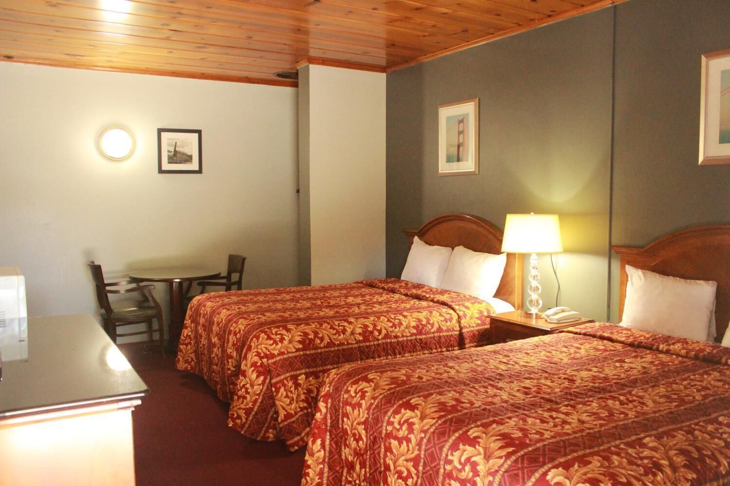 Habitació d'hotel amb dos llits, un escriptori i una cadira.