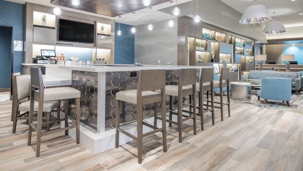 Cozinha moderna com ilha central, banquetas e iluminação pendente.