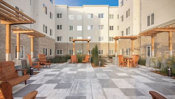 A courtyard with outdoor seating, a pergola, and a view of the building's facade.
