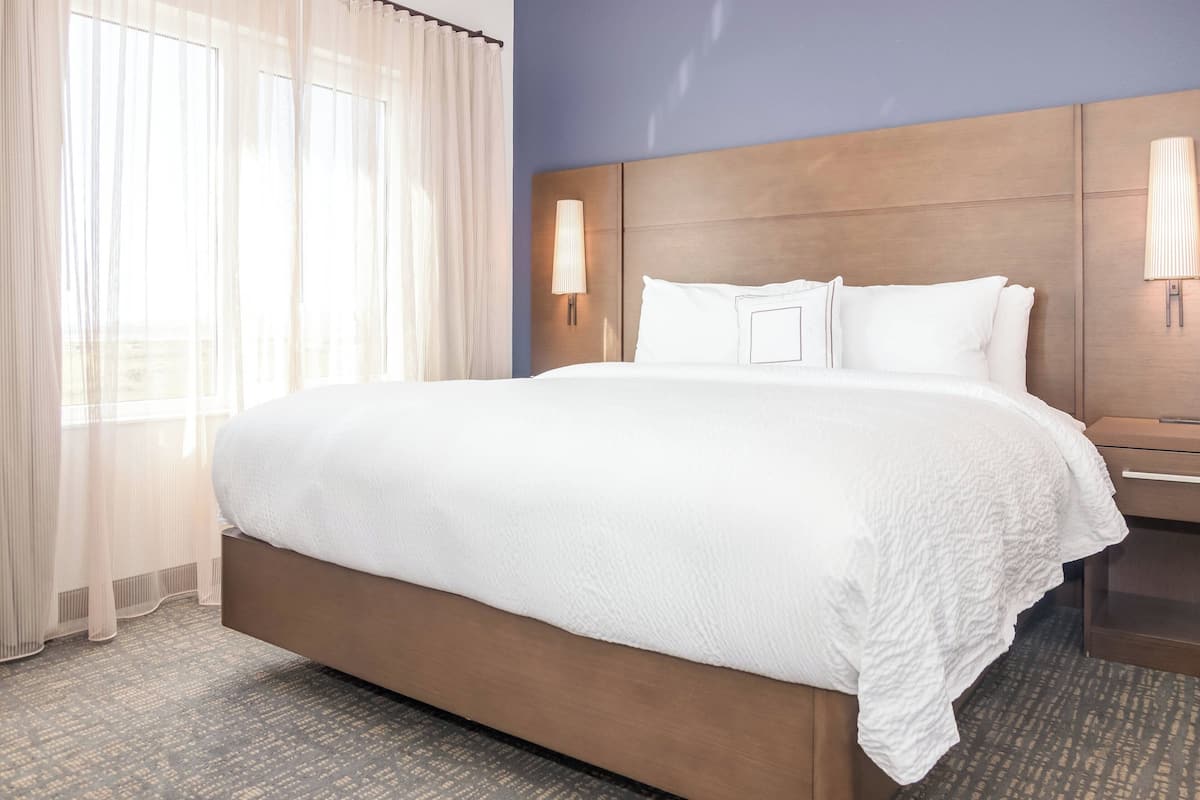 A hotel room with a large bed, a wooden headboard, and two bedside lamps.