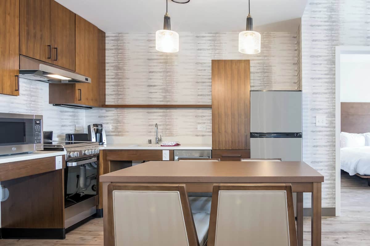 A modern kitchen with wooden cabinets, stainless steel appliances, and pendant lighting.