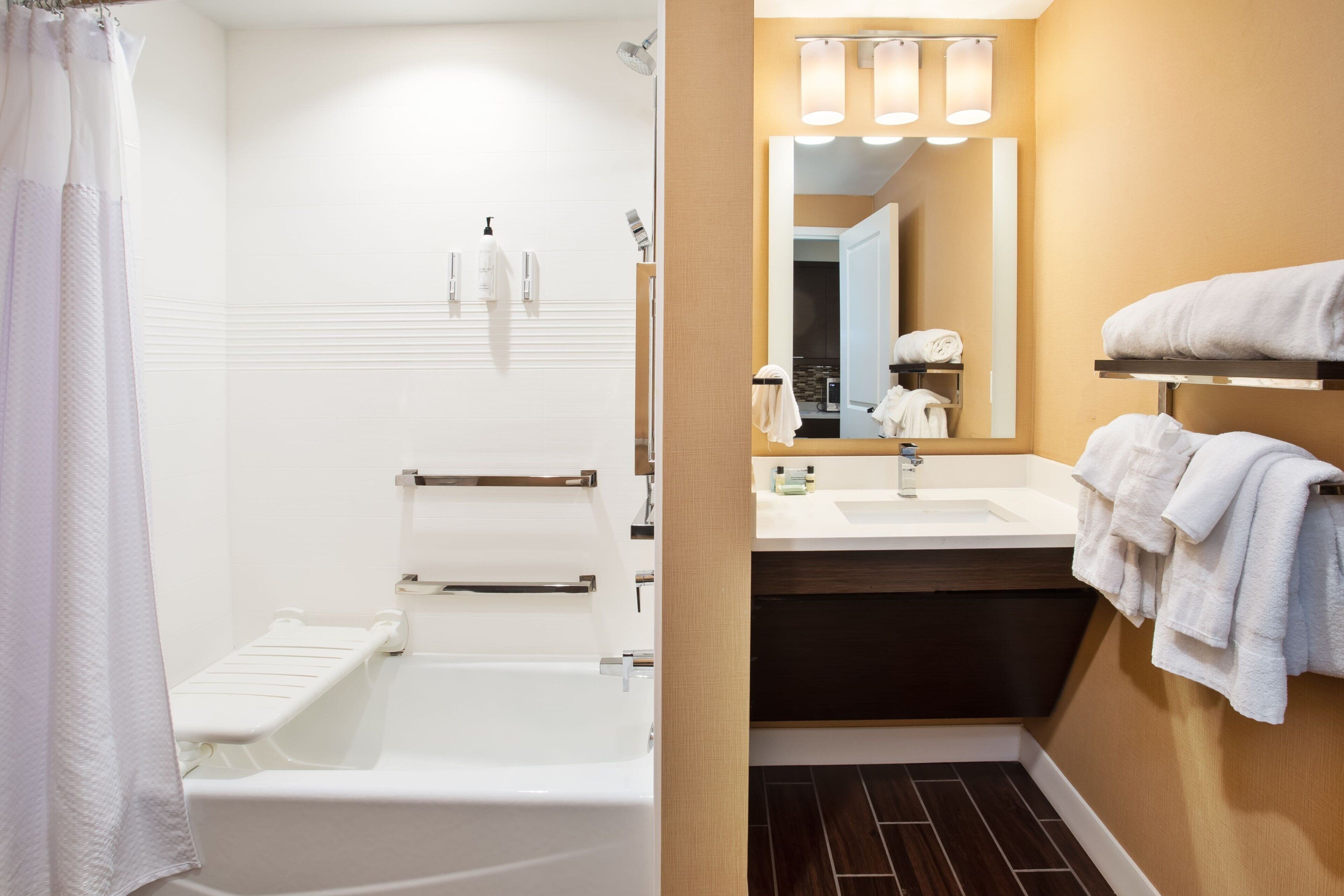 A modern bathroom with a bathtub, a shower, a sink, and a mirror.