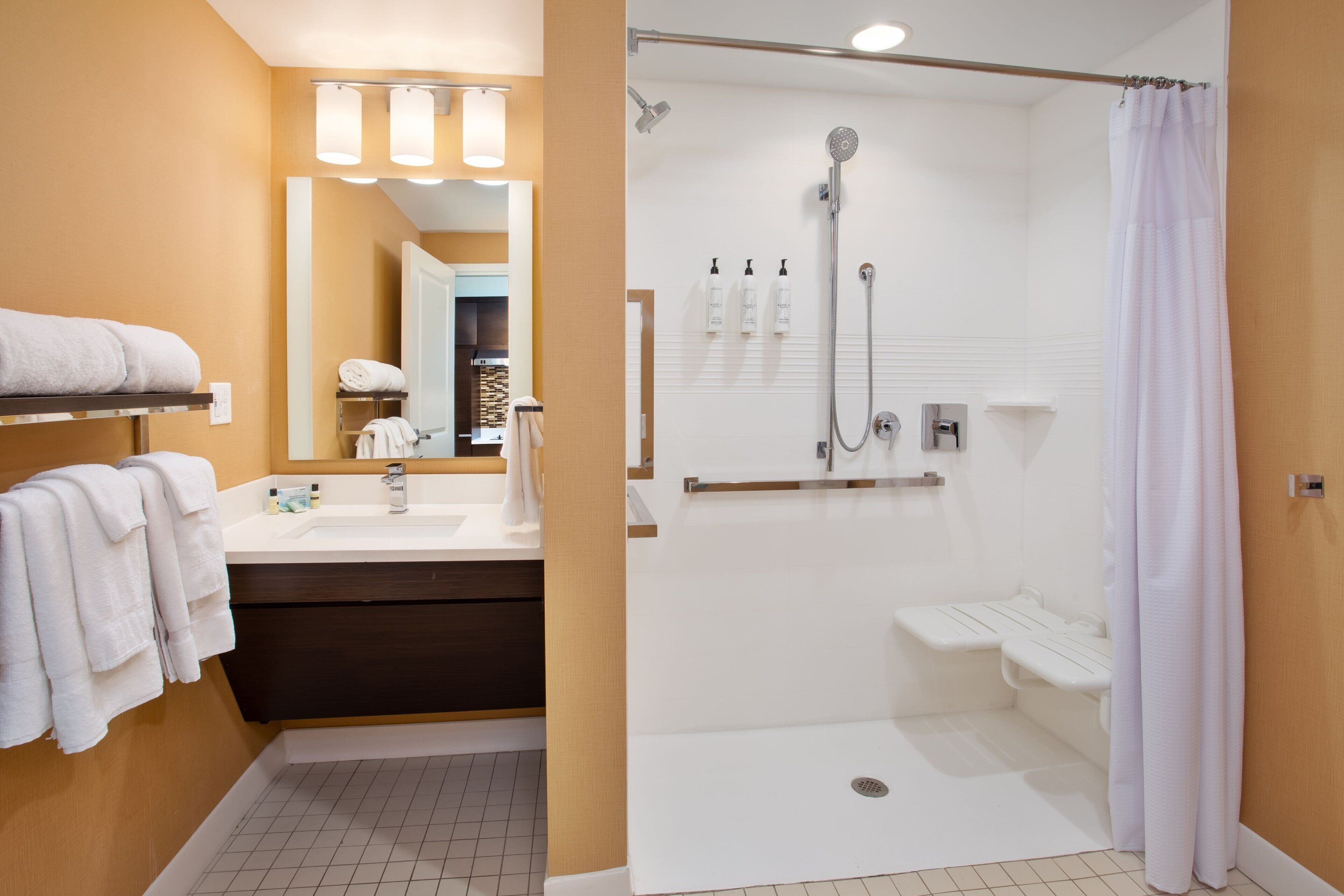 A modern bathroom with a shower, a vanity with a mirror, and a towel rack.