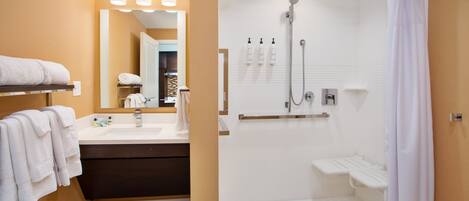 A modern bathroom with a shower, a vanity with a mirror, and a towel rack.