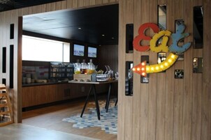 Um interior moderno com parede de madeira, área de bar com garrafas e luminária colorida.