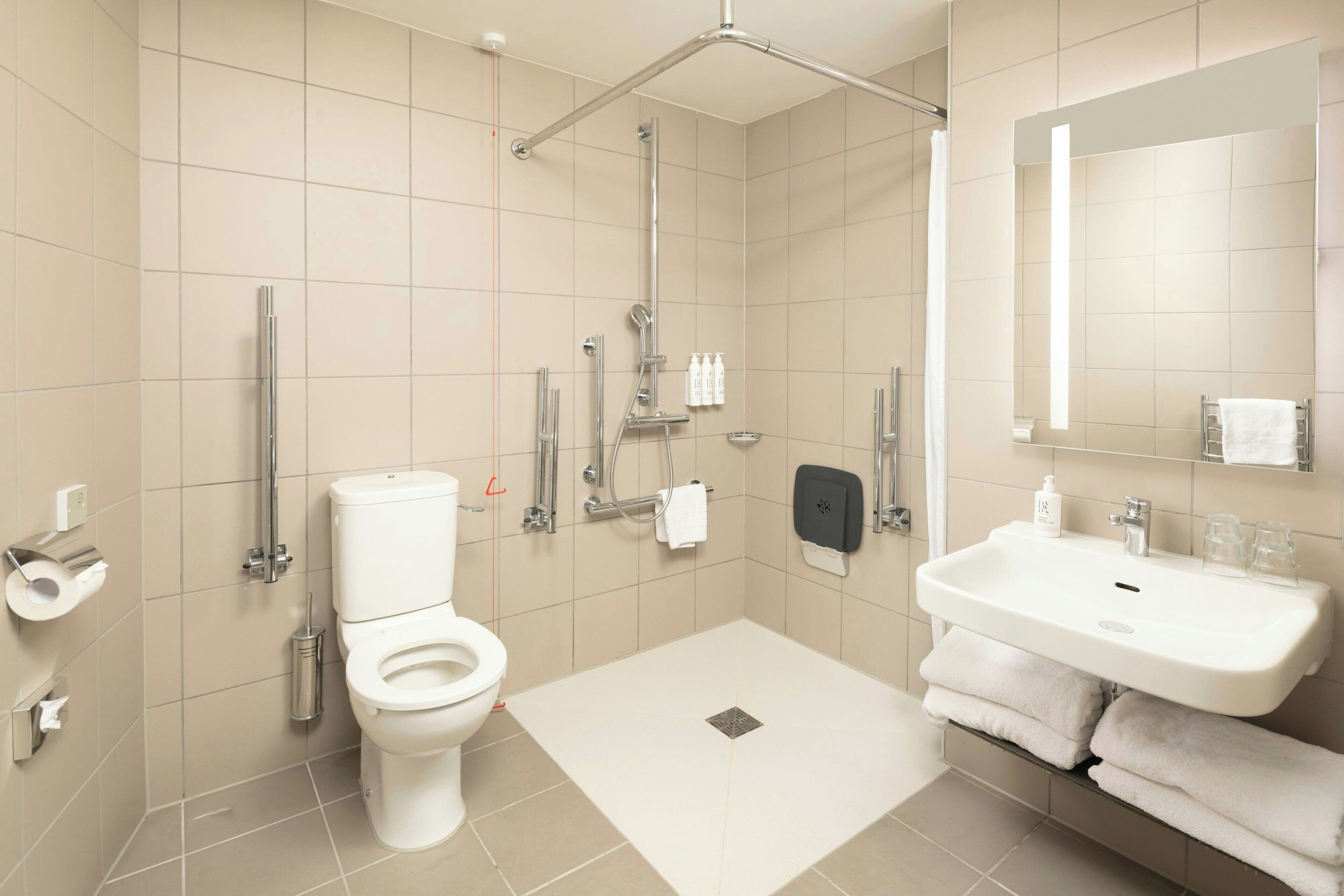 A modern bathroom with a toilet, shower, and sink.