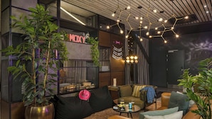 A modern living room with a sofa, coffee table, and potted plants. - Moxy York (York)