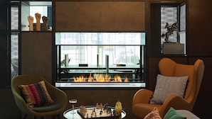 A modern lounge with a fireplace, comfortable seating, and a chessboard. - Moxy York (York)