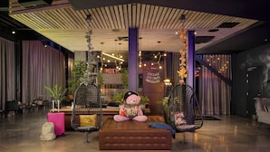 A modern interior with a plush seating area, a visible 'MOXY' sign, and hanging lights. - Moxy York (York)