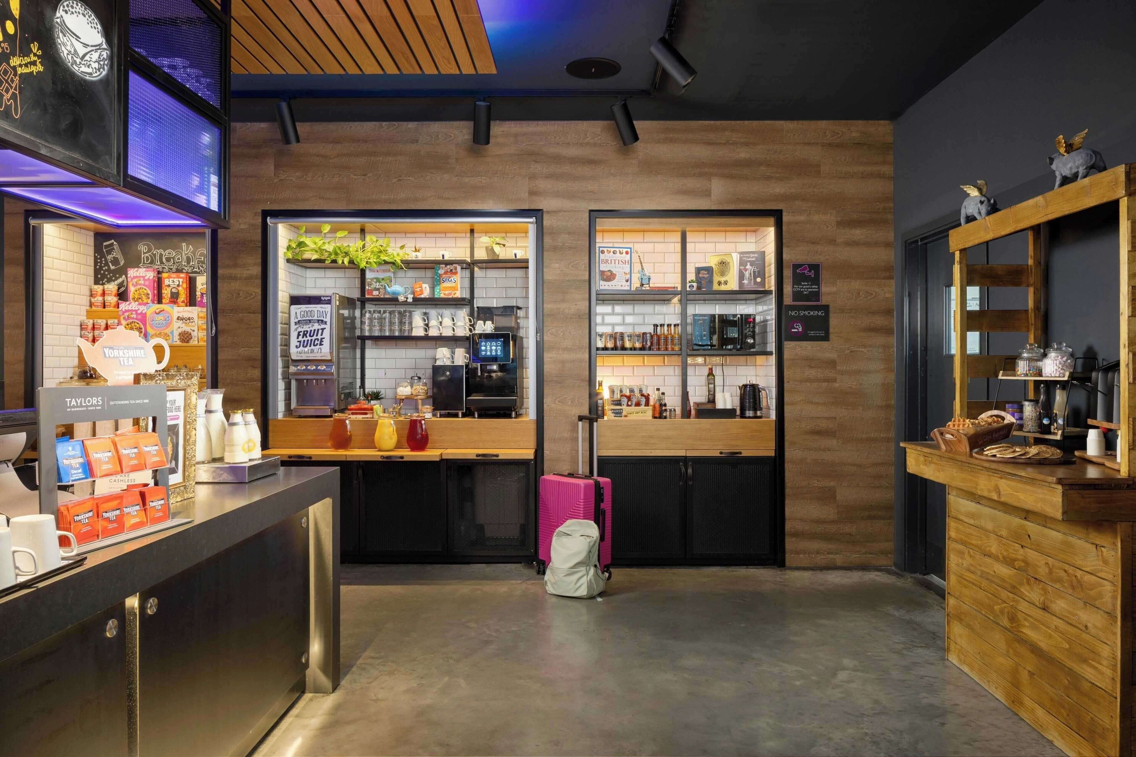 Un moderno vestíbulo de hotel con una recepción, una estación de café y un área de descanso.