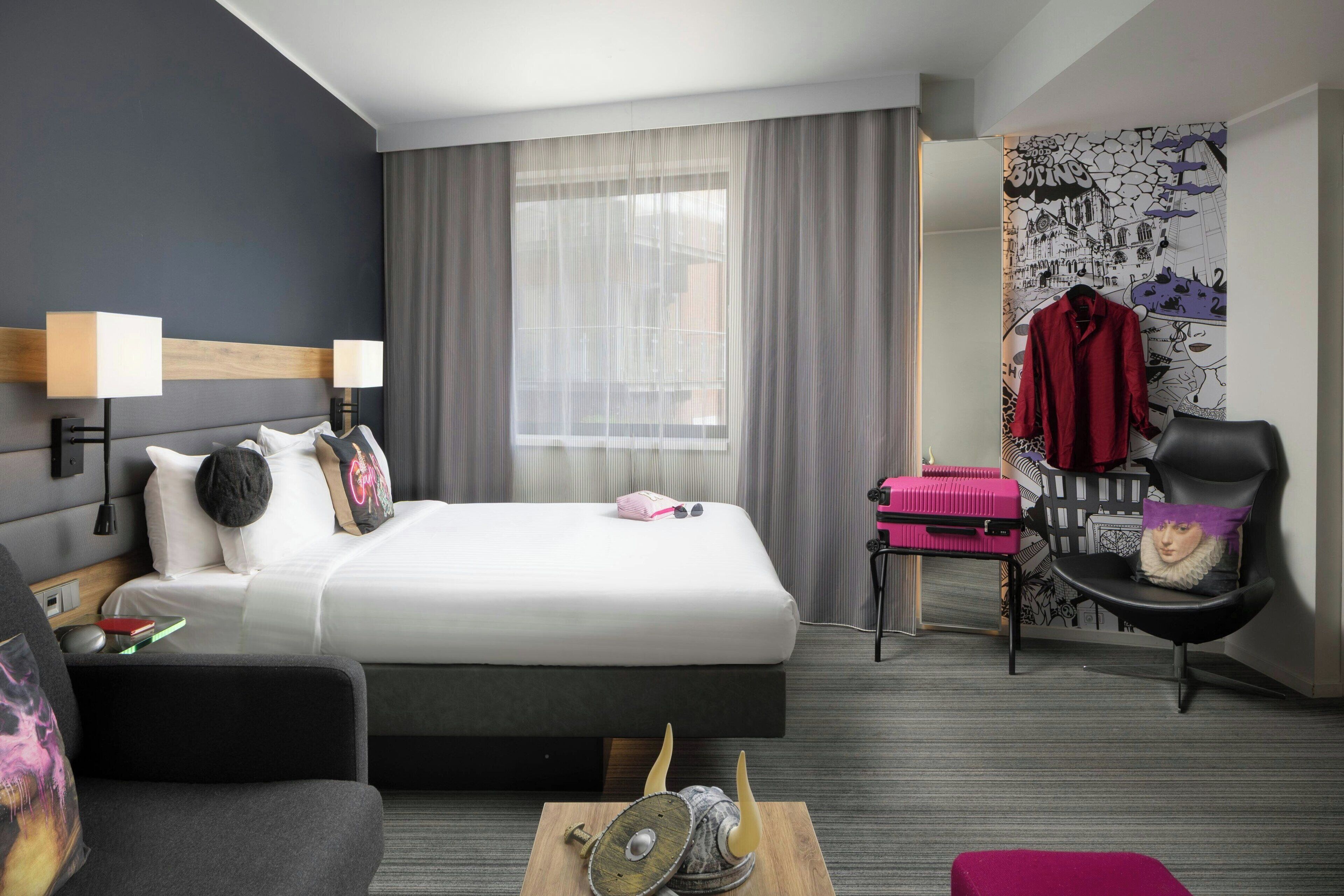 Une chambre d’hôtel moderne avec un grand lit, un bureau, une chaise et une petite table.