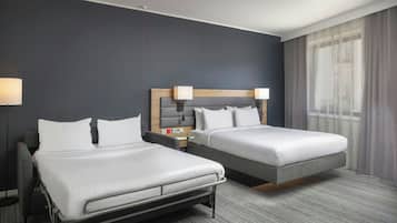 Ein Hotelzimmer mit zwei Betten, einem Schreibtisch und einer Lampe.